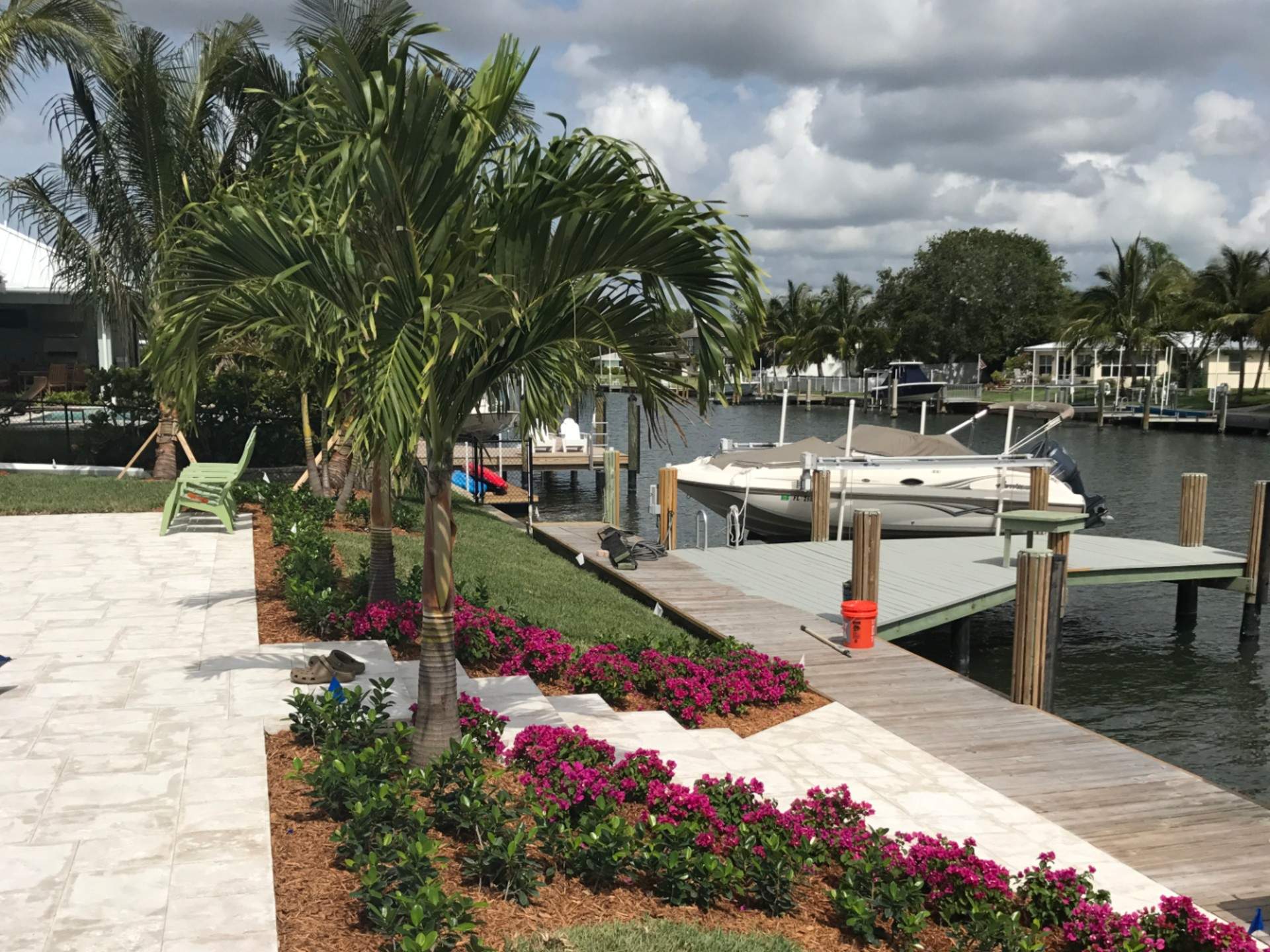 Palm trees and flowers in front of a dock with a boat